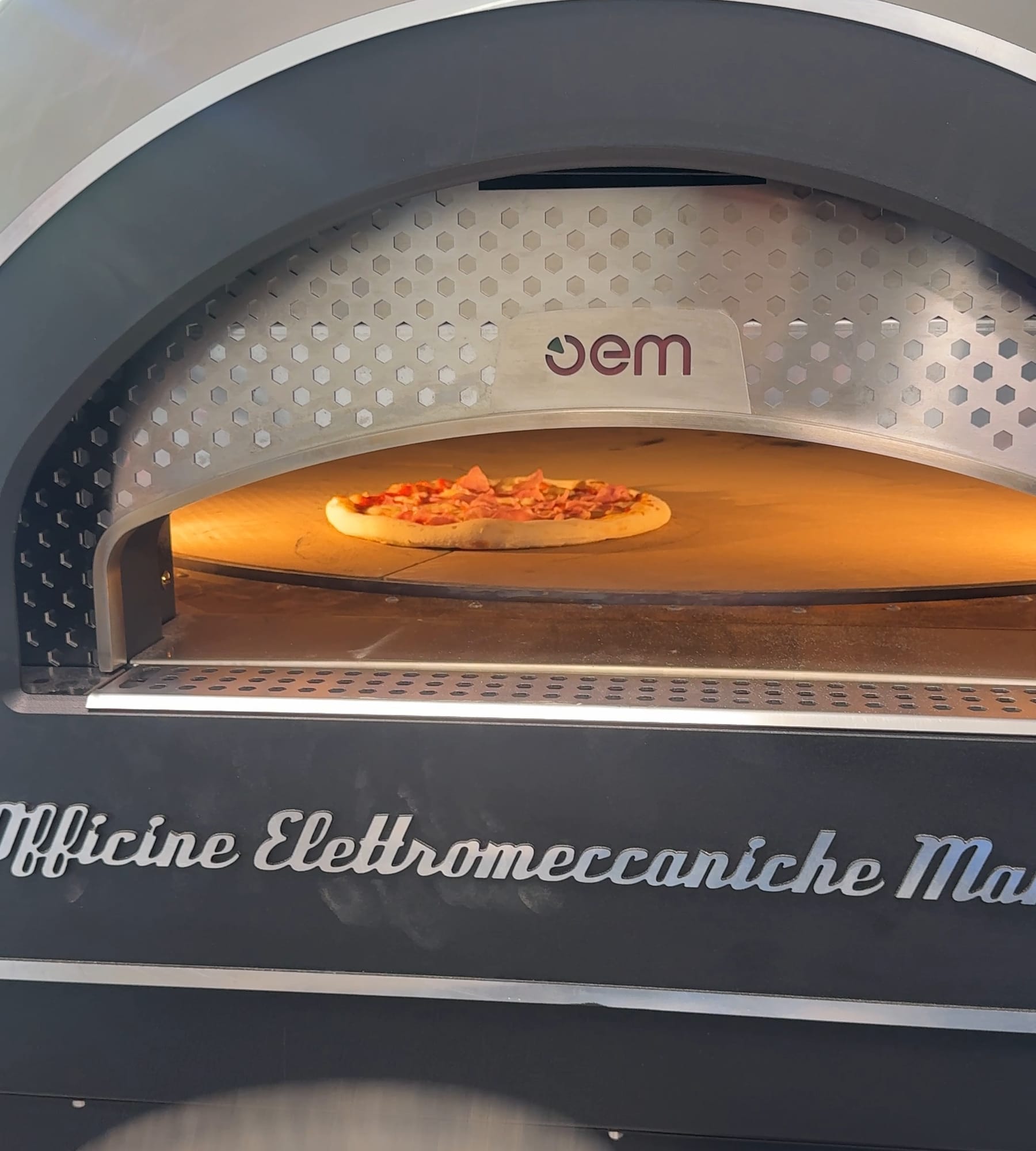 Pizza auf dem glühenden Backboden im Kuppelofen
